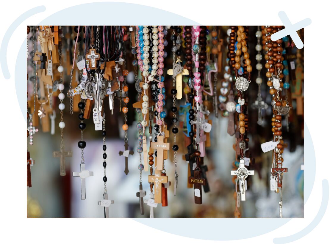 Assorted rosaries and cross pendants hanging closely together on display.
