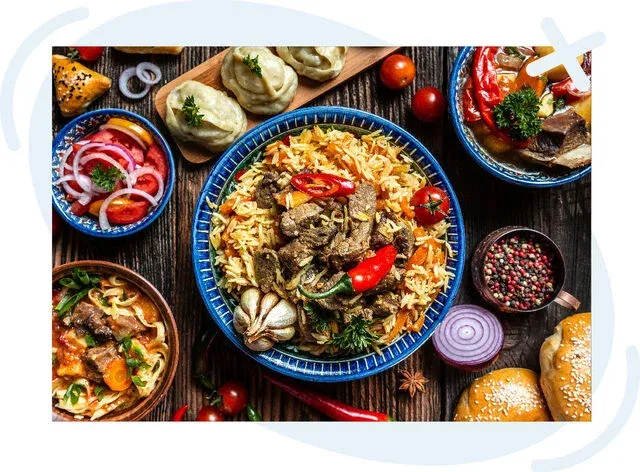 Vibrant top-down spread of Turkish-inspired dishes on a rustic wooden table, centered on a blue bowl of rice with spiced meat and colorful peppers, surrounded by salads, soups, dumplings, breads, and fresh garnishes.