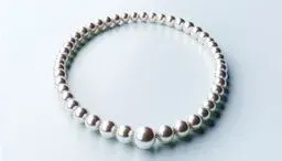 Elegant pearl necklace arranged in a perfect circle on a pale, glossy surface