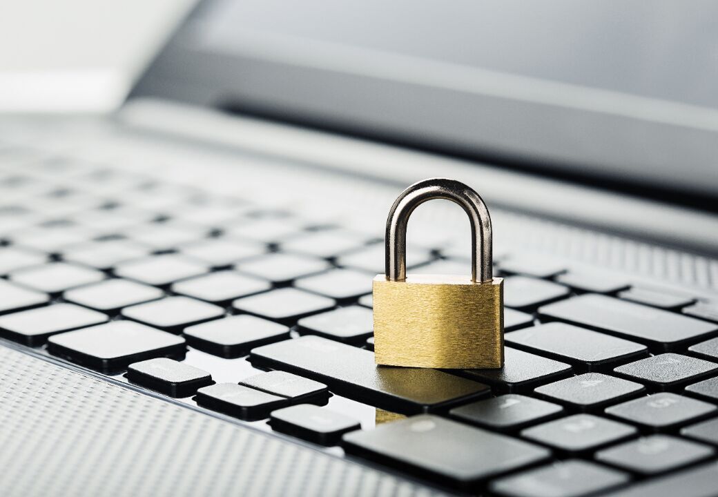 Small brass padlock placed on a laptop keyboard, symbolizing cybersecurity and data protection.