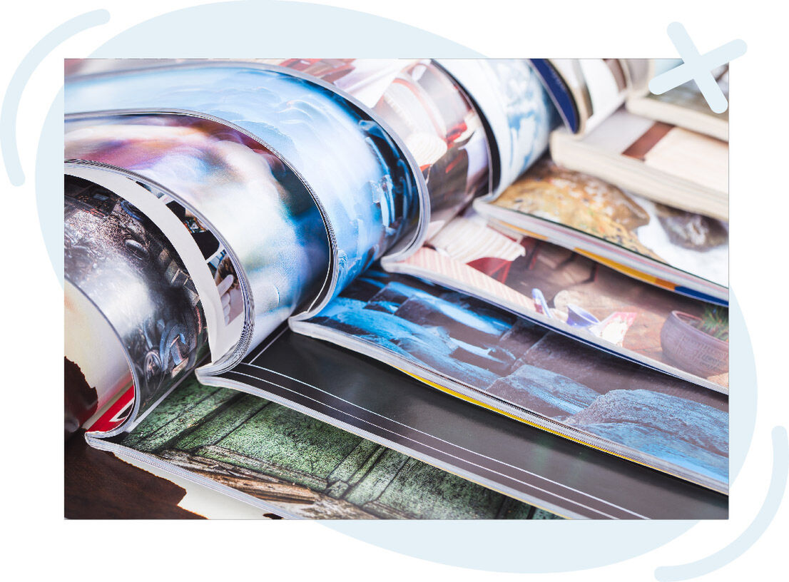 Close-up of open photo books with glossy pages curling, showing colorful images and layouts.