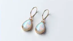 Pair of gold drop earrings featuring teardrop-shaped opals with small accent stones above each gem, set against a light background.