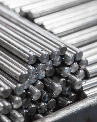 Stack of shiny cylindrical metal rods bundled together in an industrial setting