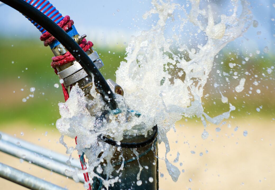 Close-up of water gushing from a metal pipe connection outdoors.