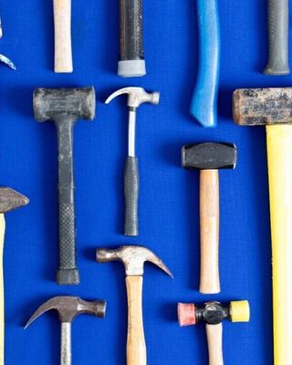 Assorted hammers and mallets arranged flat on a bright blue background.