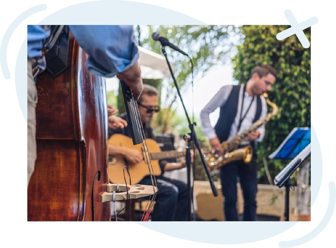 Outdoor jazz band performing with double bass, guitar, and saxophone.