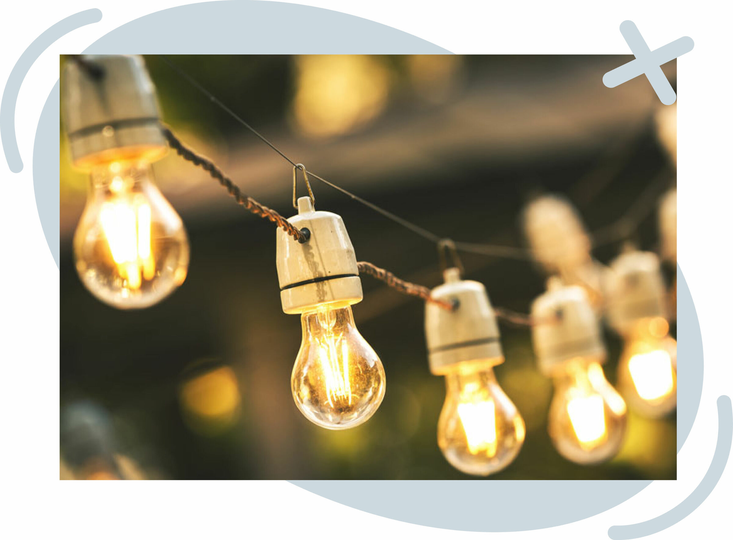 Close-up of glowing string lights with vintage-style bulbs hanging outdoors at dusk, creating a warm, cozy ambiance.